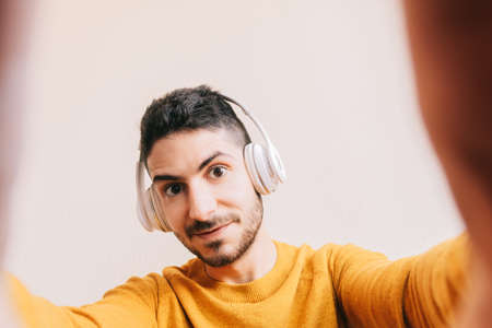 Close-up of the face of a young adult gamer with wireless headphones and expression of excitement,...