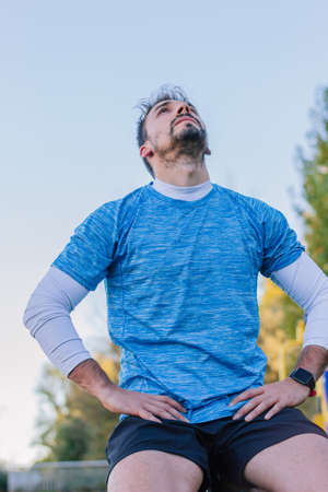 Tired 30s adult man resting after intense outdoor workout. Concept of exhausted, muscle break,...
