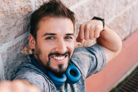 Portrait of a Caucasian young adult man looking at the camera while showing his bicep muscle by...