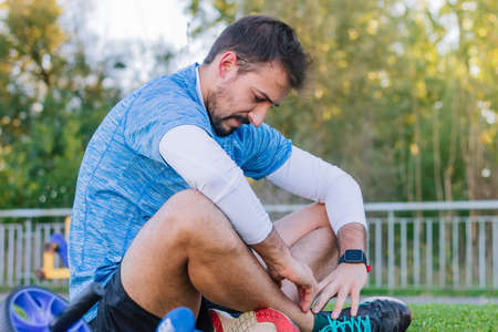 Tired athlete man resting on the track floor after intense outdoor training. Concept of exhaustion,...