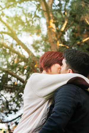 Vertical image of a young couple in love, enjoying the day in the forest, playing and kissing in nature.の写真素材