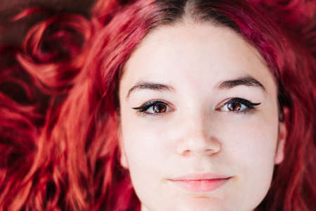 Top portrait of young and teenage woman with white skin and red, shiny, wavy hair.の写真素材