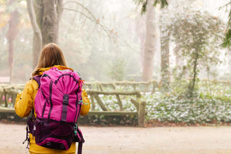 An adventurous female hiker, walking through the mountains in nature on a rainy day, wearing a...