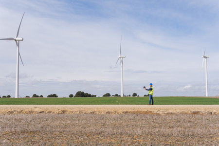 Wind farm with electric generators in operation with an industrial engineer checking the operation...