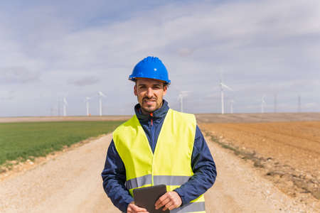 Portrait of a young adult male worker at a renewable energy plant. Image of a company that generates electricity through wind turbines.の写真素材