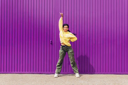 Full body of a young woman dancing outdoors with a purple background and yellow clothes. Concept of music, dance, hip hop, trap, reggaeton, alternative, pop, rock.の写真素材