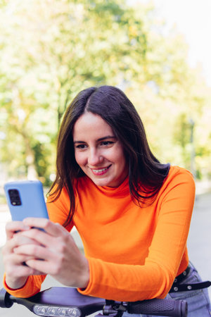 Smiling young woman using mobile phone outdoors. Technology and youth conceptの写真素材