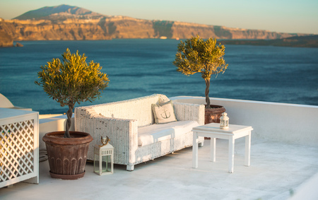 Outdoor white table and sofas on terrace overlooking sea, Oia Village, Santorini, Cyclades, Greeceの写真素材