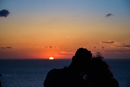 Silhouette of a loving couple on the background of the setting sun, islands and sea. Santorini. Greece. Just married. Walk at sunset. Romantic scene.の写真素材