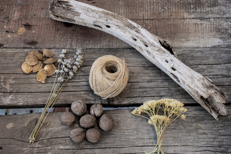 Sprigs of herbs, walnuts, string and wooden branch on wooden background. Vintage style.の写真素材