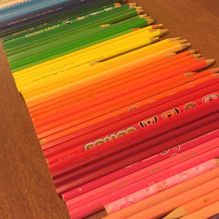 Colored pencils arranged according to the colors of the rainbow, on a brown wooden table.の写真素材
