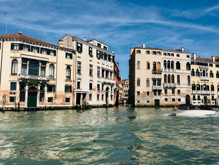 View of a sector of buildings typical of Venetian architecture, on the Grand Canal in Venice. The sky is blue and the water shows a greenish tint.の写真素材