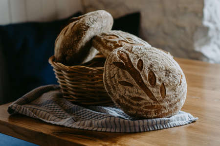 Traditional handmade, homemade sourdough bread in the basket, wooden background, blue teatowelの写真素材