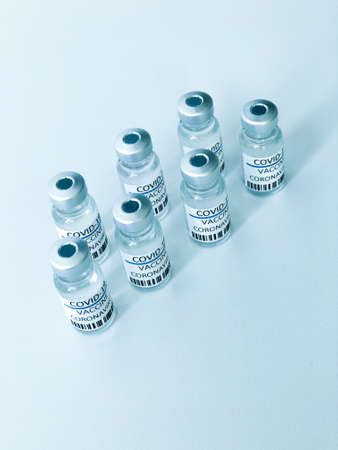 Organized COVID-19 vaccine bottles over a white table