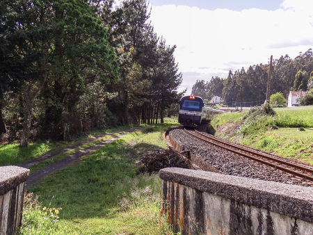 The Transcantabrico luxury tourist train leaving a curve to face a bridgeの写真素材