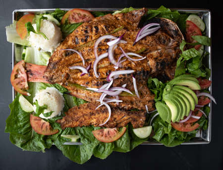 grilled fish, shaken on a salad of lettuce, avocado, tomato and onion, preparation of Mexican foodの写真素材