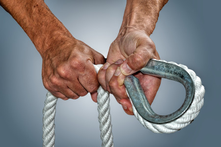 A pair of strong hands working witha big rope and a thimbleの写真素材