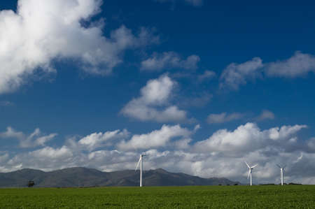 Wind turbine on open green field, blue sky and cloudsの写真素材