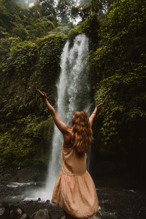 a girl poses in a bikini in a waterfall in a forest in bali