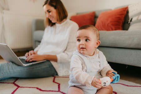 young business mother works from home with her laptop, with her baby by her side having funの写真素材