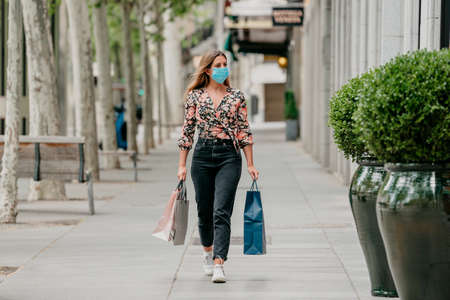 girl goes shopping down the street wearing a medical mask