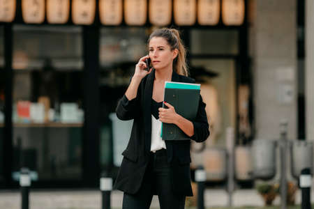 young business woman talks on the phone on the street