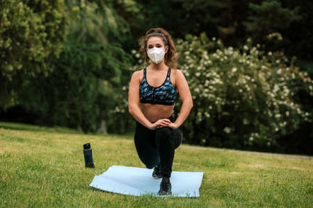 Runner wearing medical mask, Coronavirus pandemic Covid-19. Sport, Active life in quarantine surgical sterilizing face mask protection. Outdoor run on athletics track in Corona Outbreak. yoga parkの写真素材