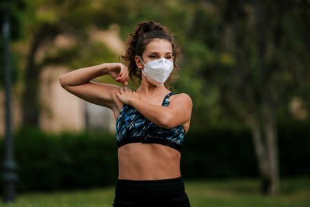 Runner wearing medical mask, Coronavirus pandemic Covid-19. Sport, Active life in quarantine surgical sterilizing face mask protection. Outdoor run on athletics track in Corona Outbreak. yoga parkの写真素材