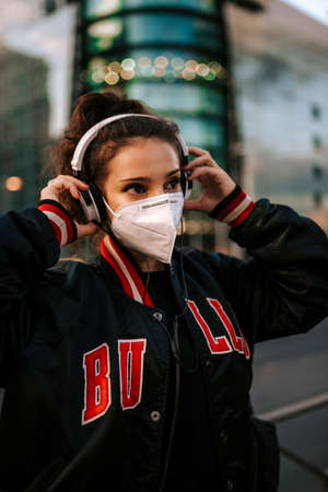 young girl dressed in sport wears medical mask on city street in spain. Coronavirus pandemic Covid-19の写真素材