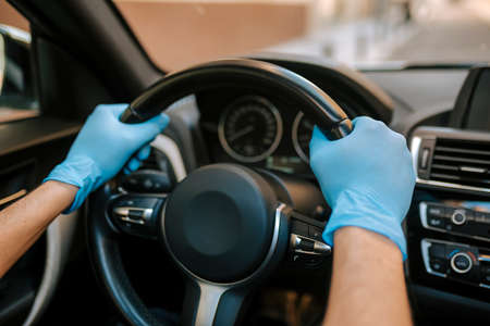 a man driving a car puts on a medical mask during an epidemic, a taxi driver in a mask, protection...