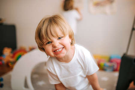 little blond boy laughs looking at camera at home. family at home. coronavirus. quarantine.の写真素材