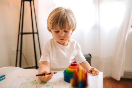 Little blond boy plays painting at home. entertainment during quarantine. family at home...