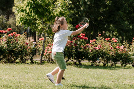 Funny little boy catching soap bubbles in the summer on nature little boy, has happy fun with cheerful smiling face. Carefree child Running and jumping on green summer meadow, catching soap bubblesの写真素材