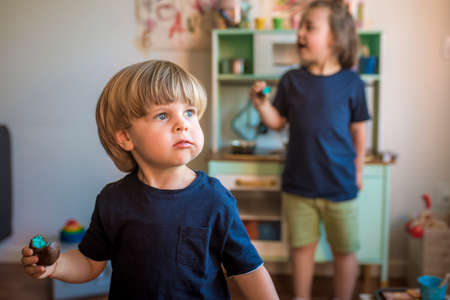 Little blond boys play with a toy kitchen at home during quarantine. Fun at home. family entertainmentの写真素材