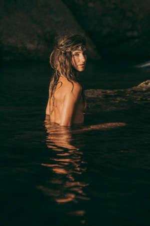 Beautiful hippie girl poses without a top on an Ibiza beach. Girl in Ibiza coveの写真素材