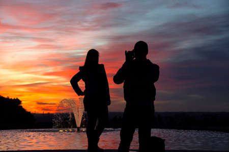 silhouette of a man holding a cellphone taking pictures outside during sunrise or sunset. Madrid.の写真素材