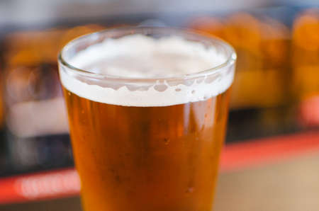 Close up of a refreshing pint glass of beer at a bar.
