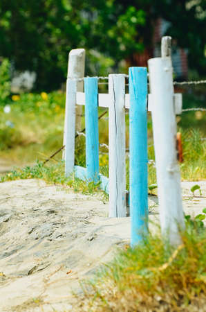 Fence posts on a beach with sand and grass. The colors are alternative between blue and white.の写真素材