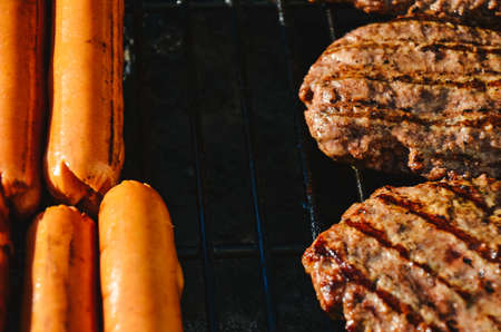 Cooking deli style hot dogs and hamburgers on a grill.の写真素材