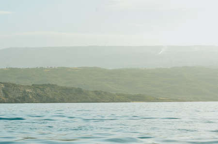Water in the foreground. There are different layers of mountains in the background. The mountains...
