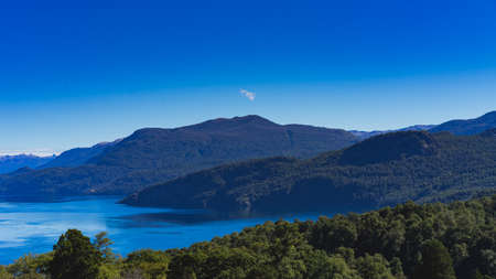 A lake with mountain and trees. Overall, the photo is very blue. This was taken in Barioloche Patagoniaの写真素材