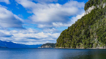 There are a lot of fluffy clouds and the lake is showing a few ripples.