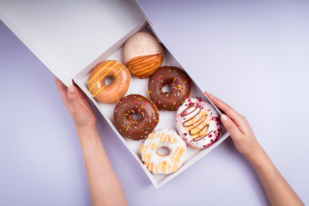 young woman holding box of sweet donuts - colorful photography - top viewの写真素材