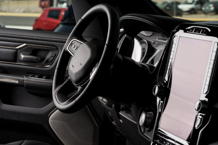 Front part of new automobile. modern black interior, steering wheel, and touch screen center console