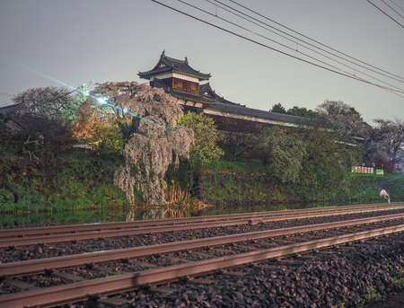 Koriyama Castle  with Cherry blossoms in front of train tracks at night.のeditorial素材