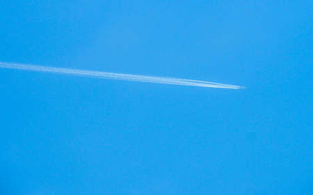 Airplane flying through blue sky with vapor trails