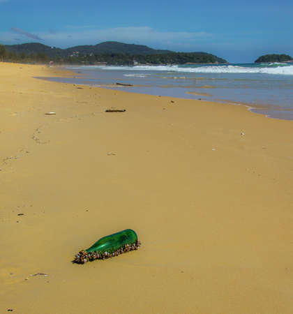 Bottle washed up onto deserted beach  covered in barnicles from the oceanの写真素材