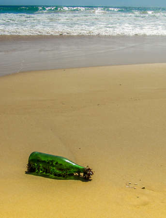 Bottle washed up onto deserted beach  covered in barnicles from the oceanの写真素材