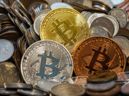 Gold, Silver and Bronze Bitcoin crypto currency coins in amoung large stack of coinsの写真素材