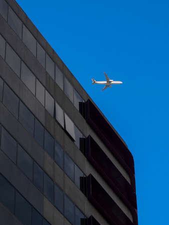 AUSTRALIA, MELBOURNE - January 07, 2015: Comercial airplane flying over office buildingのeditorial素材